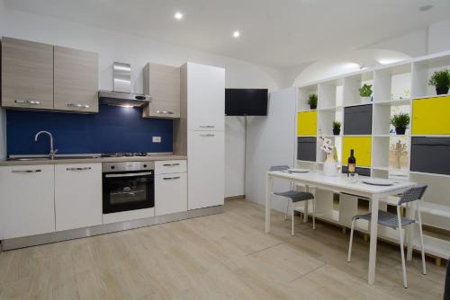 a kitchen with white cabinets and a table with chairs at Ficodì apartments in Alcamo