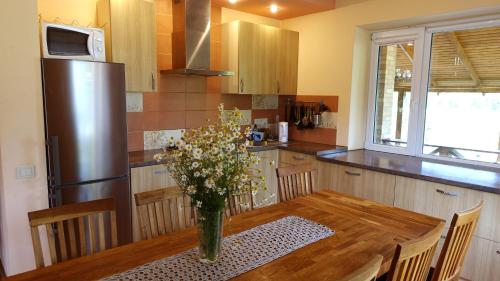 a kitchen with a wooden table with a vase of flowers at Raudonkalnis in Mankiškiai