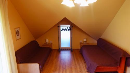 a attic room with two couches and a window at Raudonkalnis in Mankiškiai