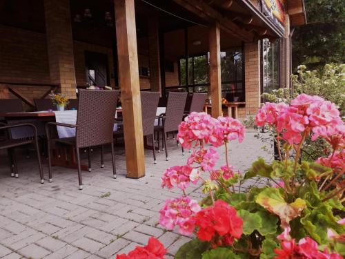 a patio with pink flowers and tables and chairs at Raudonkalnis in Mankiškiai