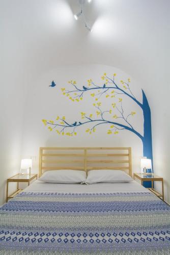 a bedroom with a bed with a tree mural at Ficodì apartments in Alcamo