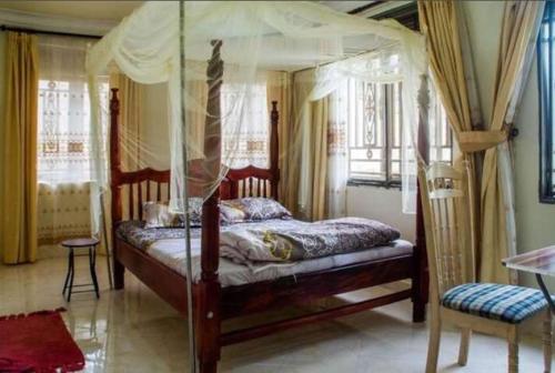 a bedroom with a canopy bed and a chair at Palace Hotel in Mbarara