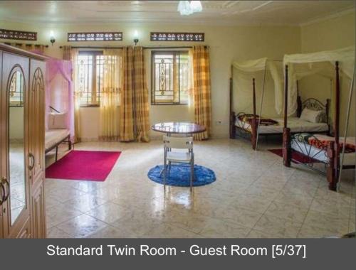 a room with a room with two beds and a table at Palace Hotel in Mbarara