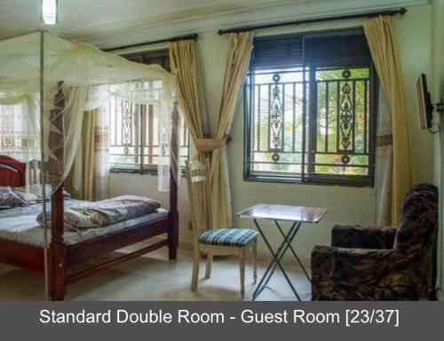 a bedroom with a bed and a table and a chair at Palace Hotel in Mbarara