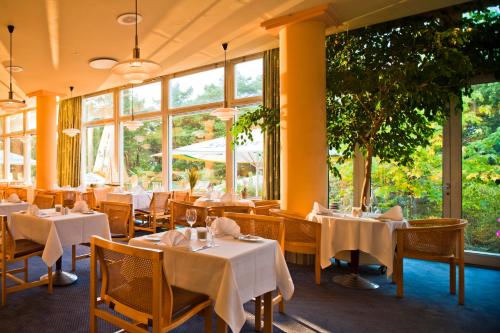 ein Restaurant mit Tischen und Stühlen und großen Fenstern in der Unterkunft Baltic Zinnowitz - Hotel mit Meerwasserpool und Thermalbad in Zinnowitz