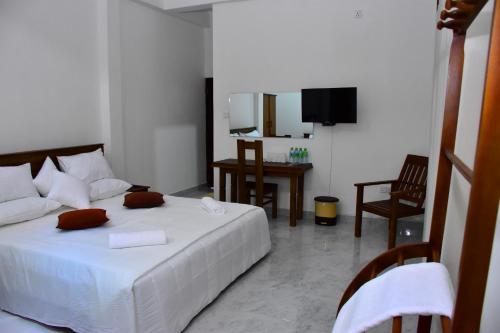 sypialnia z białym łóżkiem, stołem i krzesłami w obiekcie Ella, Nine Arch Holiday Resort w mieście Ella