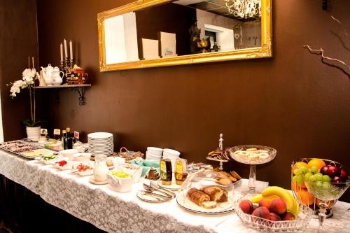 a table with food and fruit on it with a mirror at Trubarjev Art Boutique hotel in Laško