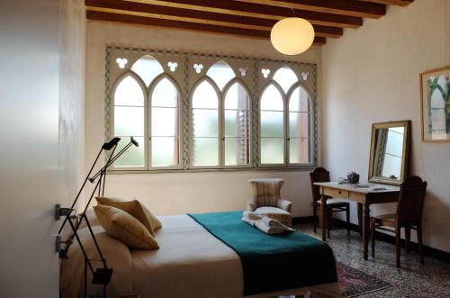 um quarto com uma cama, uma secretária e janelas em Il Selese em Monticello Conte Otto