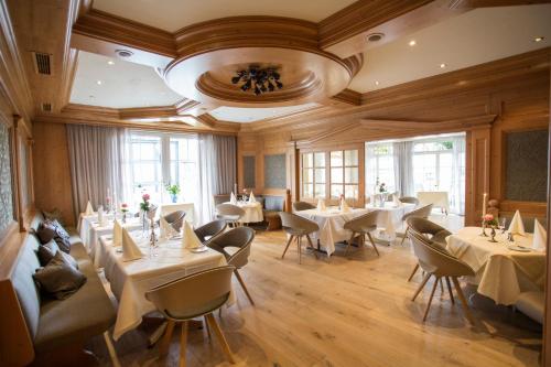un restaurante con mesas y sillas blancas y ventanas en Hotel Sauerländer Hof en Hallenberg