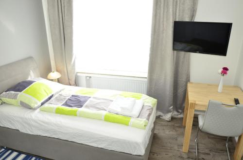a bedroom with a bed with a television and a desk at Hotel am Schloss in Paderborn