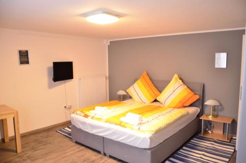 una camera da letto con un letto con cuscini gialli e arancioni di Hotel am Schloss a Paderborn