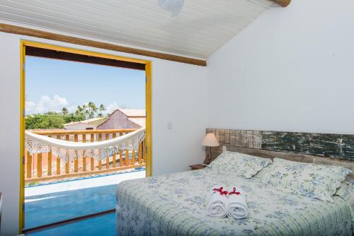 ein Schlafzimmer mit einem Bett und einem Balkon in der Unterkunft Pousada Rosa dos Ventos in Praia do Forte