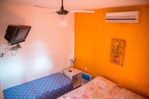 a bedroom with a bed and a tv on the wall at Suítes do Caboclo in Ilhabela