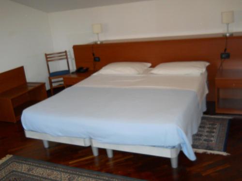 una camera con 2 letti bianchi e una testiera in legno di "Villa Bruna" a Legnago