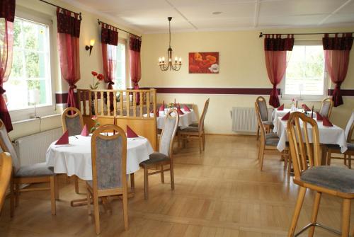 ein Esszimmer mit Tischen, Stühlen und roten Vorhängen in der Unterkunft Kastanienhof Hotel garni in Zinnowitz
