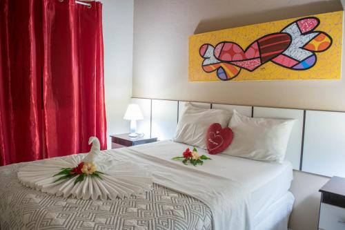 a hotel room with a bed with two flowers on it at Pousada Sol e Luna in Pipa