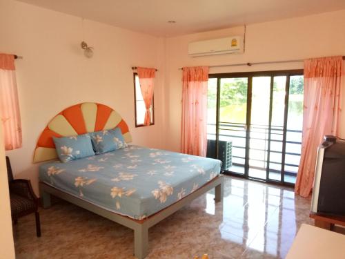 a bedroom with a bed and a large window at Baan Suan Chiva Saran in Nong Bua Lamphu