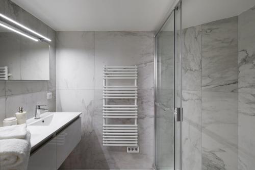 a bathroom with a shower with a sink and a glass shower door at Apartment Le 1727 in Saint Malo