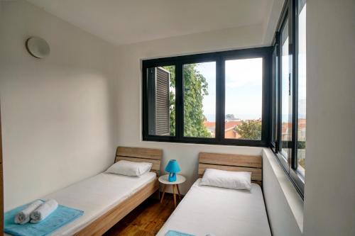 two beds in a room with two windows at Apartments Minja Nerin in Petrovac na Moru