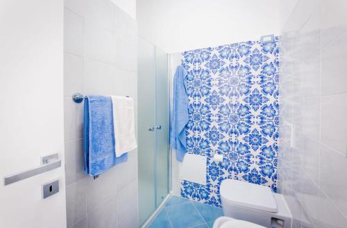 a bathroom with a toilet and a blue and white tile wall at Zagma Un Passo Dal Mare in Canneto