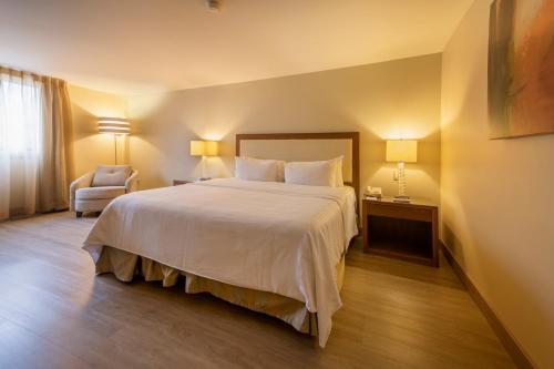 a hotel room with a large bed and a chair at Antaris Valle in Monterrey