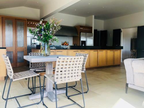a kitchen with a table with chairs and a vase of flowers at Cable Bay Villa in Oneroa