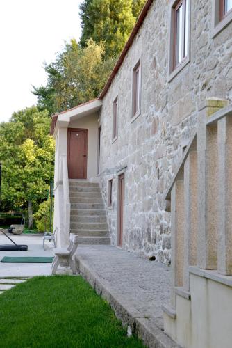 a building with a bench next to a house at Quinta dos Jasmins in Paços de Ferreira