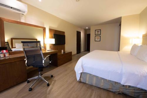 a hotel room with a bed and a desk and a chair at Antaris Valle in Monterrey