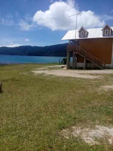 a building with a large field of grass next to a lake at Cabañas Islas de Tziscao in Santiago