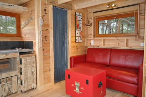 un soggiorno con divano rosso e scatola rossa di Cabane des Guernazelles a Valderoure