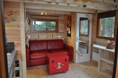 uma sala de estar com um sofá vermelho numa pequena casa em Cabane des Guernazelles em Valderoure