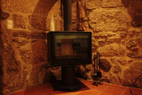 a television on a pole in front of a stone wall at Casa do Notário in Amares