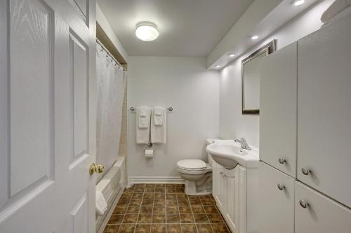 a white bathroom with a toilet and a sink at Parkside House in Barrie