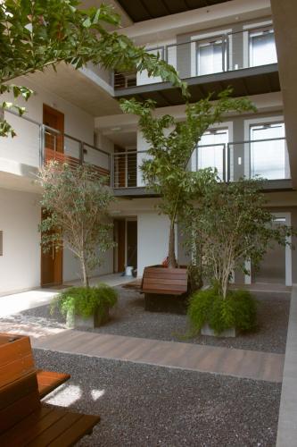 a building with two trees and a bench in a courtyard at START Villa Morra Rent Apartments in Asuncion
