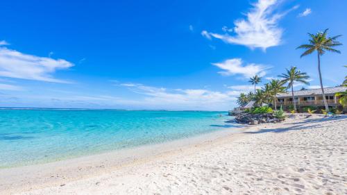 a beach in front of a resort with palm trees and the ocean at Sanctuary Rarotonga on the Beach (Adults Only) in Rarotonga
