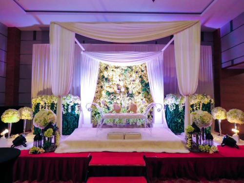 a bedroom with a bed with a canopy and flowers at StarLodge in Kampong Jerudong