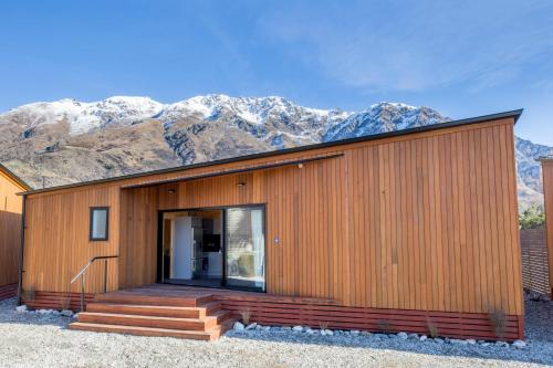 a wooden house with mountains in the background at Queenstown Top 10 Holiday Park in Queenstown