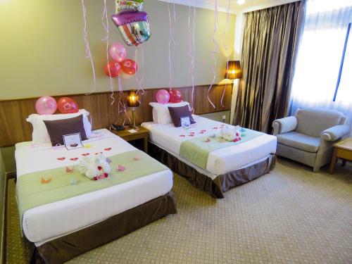 a hotel room with two beds with balloons and a chair at StarLodge in Kampong Jerudong