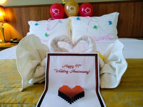a sign on a bed with swans making a heart at StarLodge in Kampong Jerudong