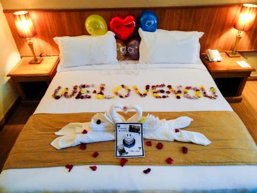 a bed with wedding clothes and balloons on it at StarLodge in Kampong Jerudong
