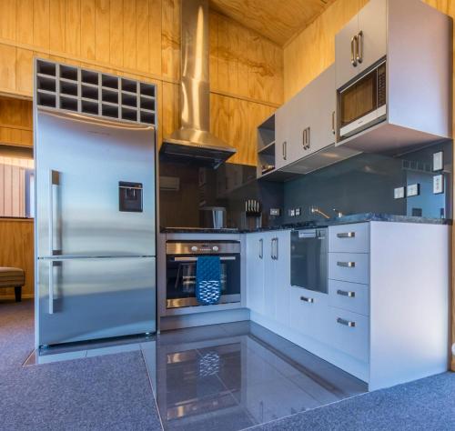 a kitchen with stainless steel appliances and wooden walls at Queenstown Top 10 Holiday Park in Queenstown