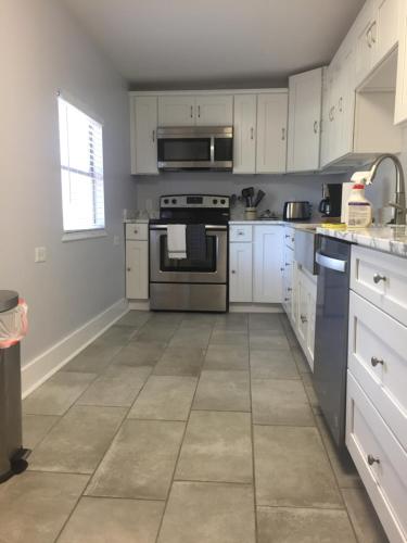 a kitchen with white cabinets and a tile floor at Villa Riberia in St. Augustine