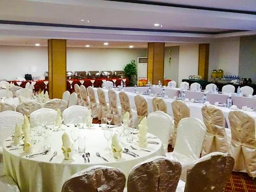 a banquet hall with white tables and chairs at StarLodge in Kampong Jerudong