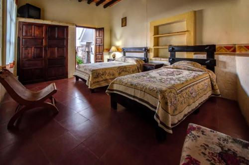 a bedroom with two beds and a chair in it at Villa San Francisco Hotel in Taxco de Alarcón
