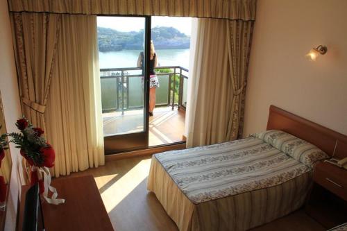 a woman standing in a hotel room with a bed at Hotel Alfar in Isla