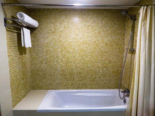 een badkamer met een bad en een groene betegelde muur bij StarLodge in Kampong Jerudong