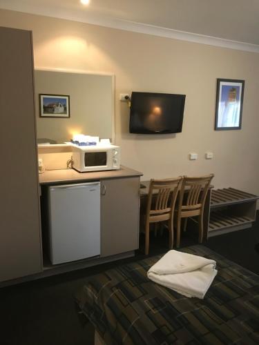 una habitación de hotel con microondas en una encimera con sillas en The Bakehouse Motel, en Goulburn