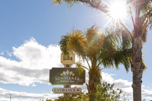 
a street sign with palm trees and palm trees at Sunseeker Motor Inn in Batemans Bay
