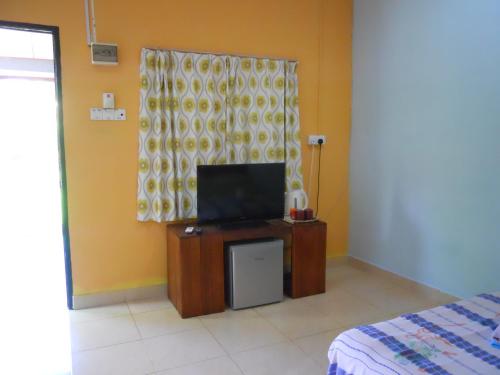 een kamer met een tv, een bed en een raam bij Rainbow Lodge in Pantai Cenang