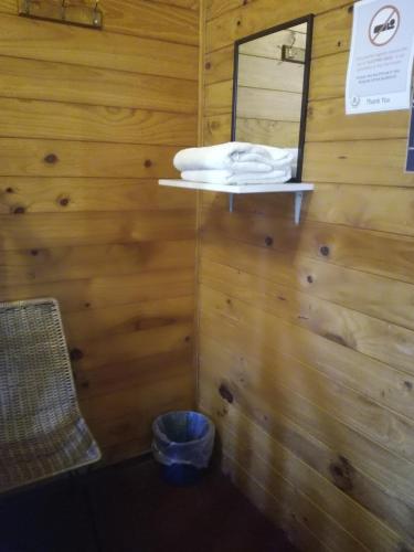 a room with a wooden wall with a mirror and a bucket at JunoHall Backpackers in Waitomo Caves